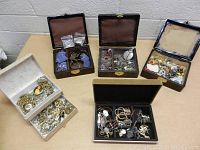 Five assorted jewelry boxes filled with various necklaces, bracelets, rings, brooches, lockets, and other mixed jewelry pieces seen from top view