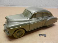 Side view of vintage metal Chevrolet coin bank with key beside it