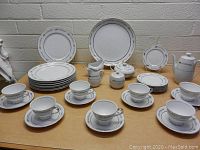Photo showing full Empress Silver Wheat china set arranged on table with plates, cups, saucers, and serving pieces.