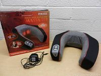 Photo showing the Homedics neck and shoulder massager along with power adapter and original box with product branding and features.