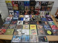 Photo showing three rows of assorted CDs on a table, featuring artists like Nirvana, Pearl Jam, Elvis, and Beastie Boys with visible album covers.