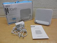 Photo of sound machine with power adapter, user manual, and original retail box showing product image and branding.