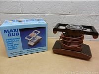 Photo showing Maxi Rub personal massage unit next to its original box with front view.