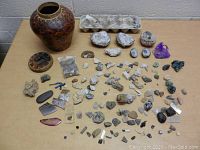 Full view of the rock collection on a table including pottery vases, geodes, agate slices, and many loose specimens.