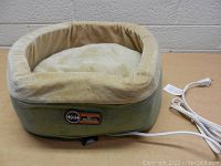 Front view of K&H heated pet bed showing beige cushioned interior, green exterior, and attached power cord.