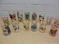 Full view of all character glasses in lot arranged in two rows on a table, showing variety of designs and sizes