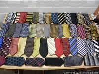 Top view of 48 men's neckties, showing variety of colors and patterns laid out flat on table.