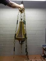 Full view of vintage hanging light fixture showing fabric shade and brass hanging chains with green accents