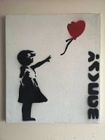 Front view of canvas showing the silhouette of a girl reaching for a red heart balloon with Banksy stencil lettering on the right side.