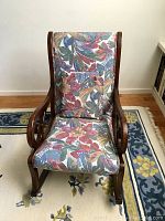 Front view of antique rocking chair showing carved wooden frame and floral upholstered seat and back