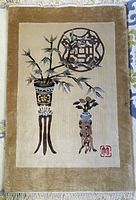 Front view of the Chinese silk tapestry showing two bamboo plants in vases with circular Chinese symbol above, bordered in beige.