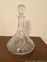 Crystal flask with stopper showing etched geometric and starburst pattern on clear crystal glass.