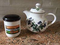 Photo of Villeroy & Boch Botanica coffee pot and Naif jar on kitchen countertop showing detail of jar's colorful countryside motif and pot's floral pattern