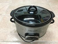 Front and side view of the Crock-Pot slow cooker with glass lid on floor tile background.