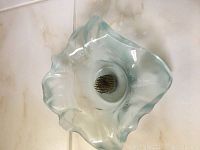 Close-up of translucent light blue glass flower display bowl showing metal floral frog inside.