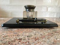 Front view of black onyx base holding glass ink well with metal lid and brass paper knife
