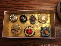 Top view of all seven collector boxes arranged in a box with gold floral interior