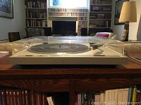 Front view of Pioneer turntable with dust cover on wooden table