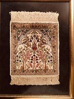 Framed oriental mini rug with floral patterns, gold frame and black matte background