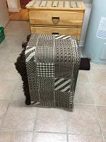 Folded Hudson Bay St. Moritz woollen bedspread with brown and cream geometric pattern and fringed ends.