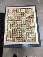 Rectangular cork board made up of various wine corks arranged neatly in a wooden frame.