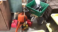 Overall view of lot showing Lesco spreader, gas cans, chainsaw case and string trimmer