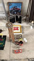 Wide shot showing the Miller Lite illuminated sign, framed monster truck picture, billiard chalk holder stand with billiard chalks, Harley Davidson shot glass set in case, and other small collectibles arranged on the floor.