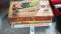 Four vintage board games stacked including Scribbage on top, The Electric Maze by Remco large box underneath, Beta-Million and American Heritage Broadside at the bottom.
