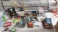 Overview of items arranged on a table including jewelry, belt buckles, decorative items, and boxes.