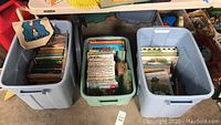 Three plastic totes filled with children's books in various sizes and formats.