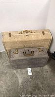 Large beige suitcase behind smaller gray suitcase on floor