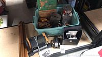 Wooden tripod, vintage camera, photo plates, developing supplies in a plastic tote bin