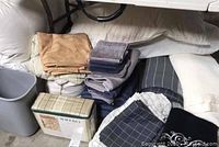 Photo showing folded beige and white sheets, towels in gray, navy and purple shades, the packaged Waverly bedding item, and the checkered comforter.