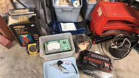 Wide view of the lot showing jack stands in box, car ramps, plastic container with Snap-On auto analyzer, trailer hitch with lock, and miscellaneous tools.