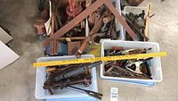 Overview of several bins containing mixed vintage heavy duty hand tools including saws, clamps, and other items.