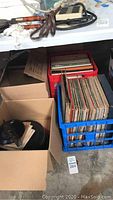 Assortment of vinyl record albums in crates and boxes on the floor.