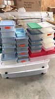 Clear plastic storage totes stacked on top of two large white under the bed storage totes with wheels.