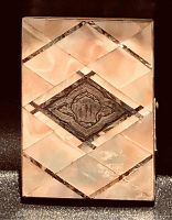 Front view showing mother of pearl and silver inlaid geometric pattern with a central engraved silver diamond shape, showing wear spots.