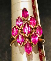 Top-down view on mandrel showing diamond-shaped cluster of nine marquise-cut rubies and mandrel reading approx. size 6