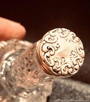 Close-up image of the ornate sterling silver screw top showing floral and scroll embossing.