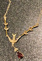 Detail of pear-shaped red gemstone drop beneath bird motif