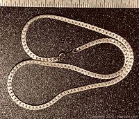 Sterling silver chain laid in a loose figure-8 shape on black surface showing entire chain and clasp details.