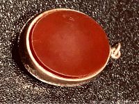 Close-up image showing the carnelian stone side, polished reddish-brown oval stone set in gold.