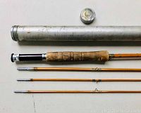 Four-piece cabbage color bamboo fly rod with cork handle and metal ends alongside silver metal rod holder tube and cap laid out flat