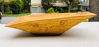 Side view showing the oblong shape and whale carving detail on wooden bowl.