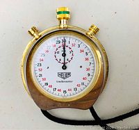 Front view of stopwatch showing white dial, black and red numerals, Heuer logo and trackmaster text