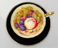 Top view of the cup showing the fruit painted design on the interior with black background and gold trim