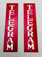 Front view of the two red and white telegram metal signs side by side showing lettering and condition.