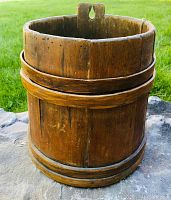 Front and side view of antique wooden barrel pail showing structure and wood staves with binding rings.