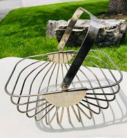 Top perspective and side views of the vintage silverplate basket showing the folding handle and wire construction.
